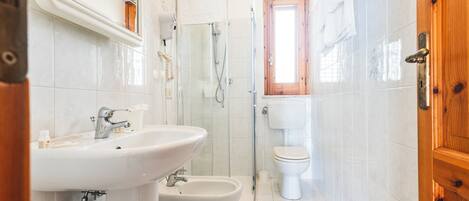 A bathroom with a sink, bidet, toilet, and glass shower enclosure.
