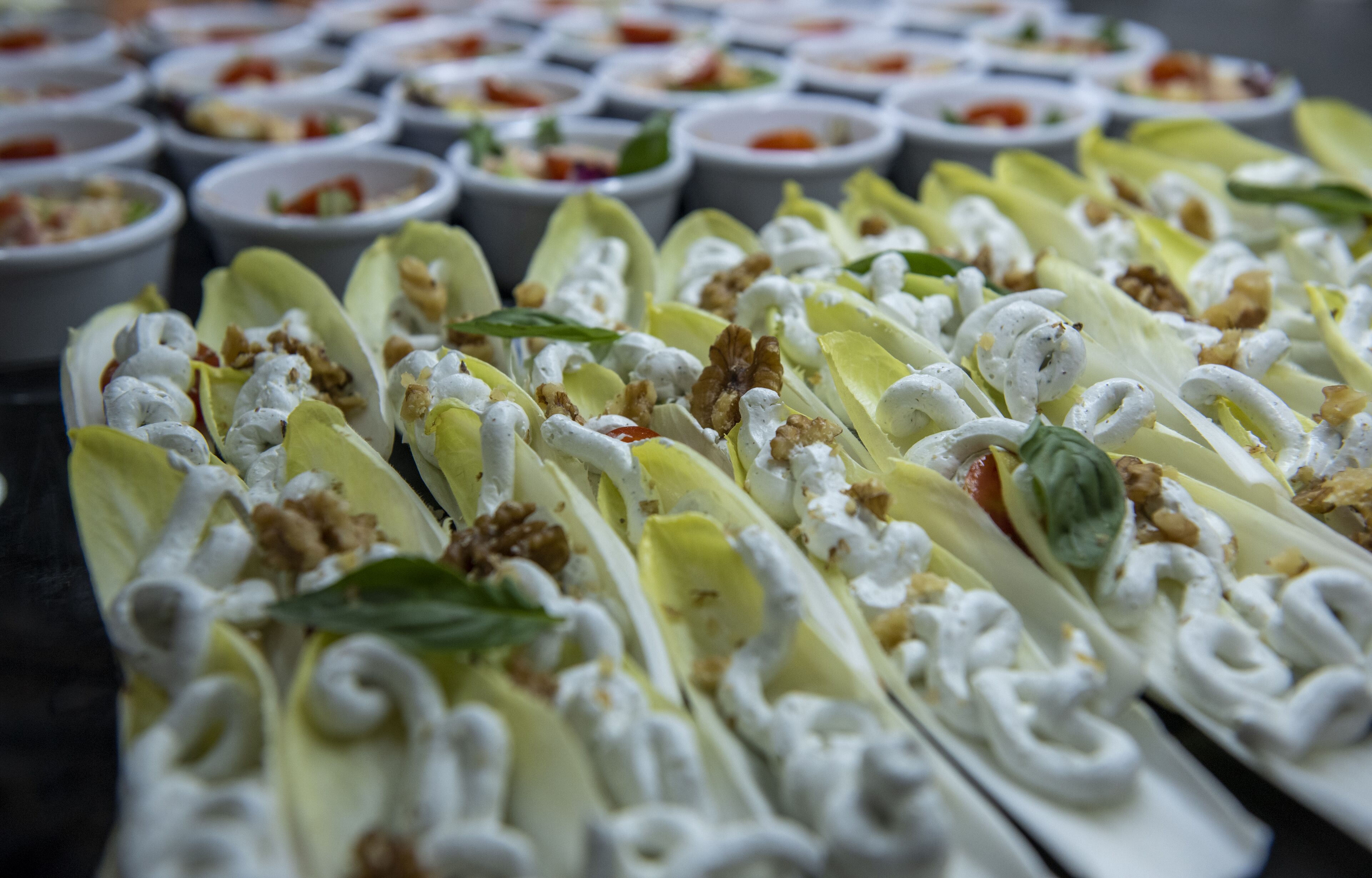 Variedad de alimentos sobre una mesa, incluyendo platos con nueces y vegetales de hoja verde.