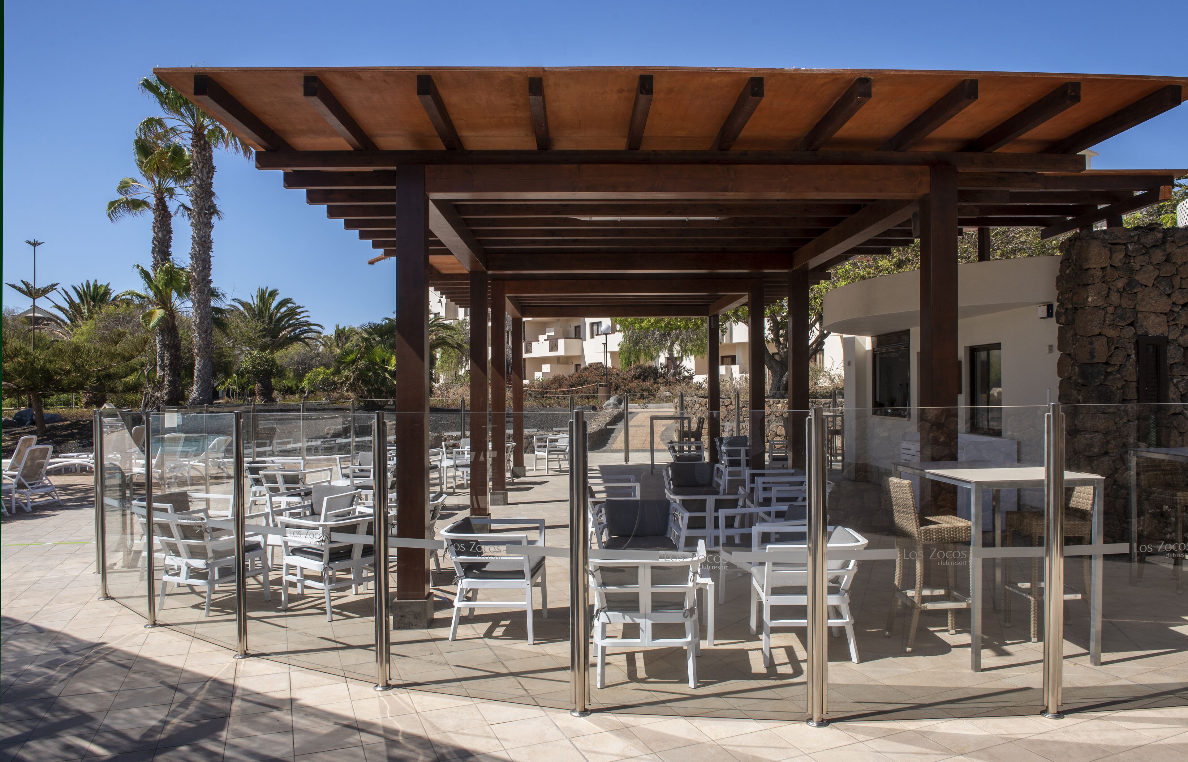 Een terras met glazen zitgedeelte en een houten pergola.