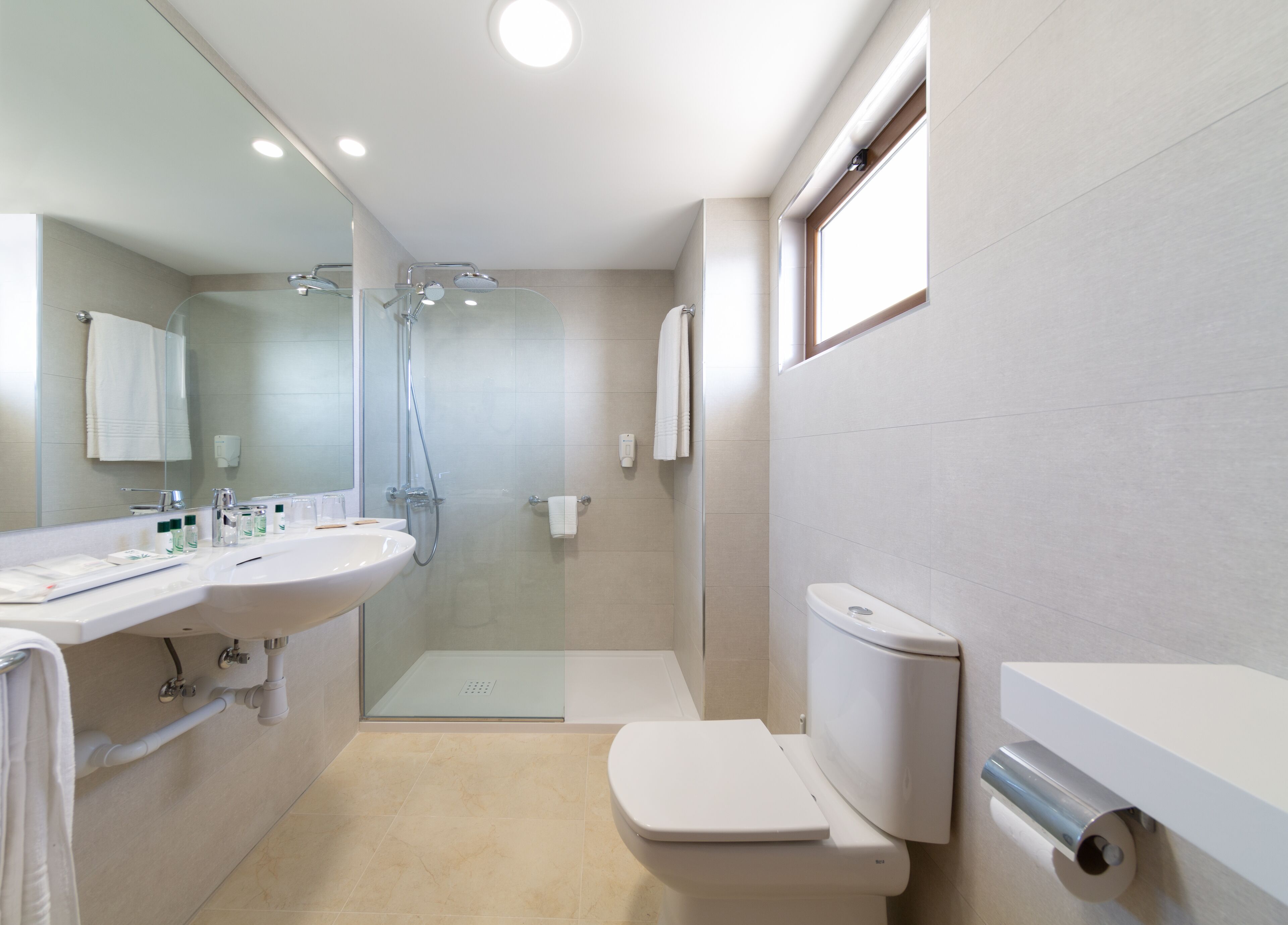 A modern bathroom with a glass-enclosed shower, a white sink, and a toilet.