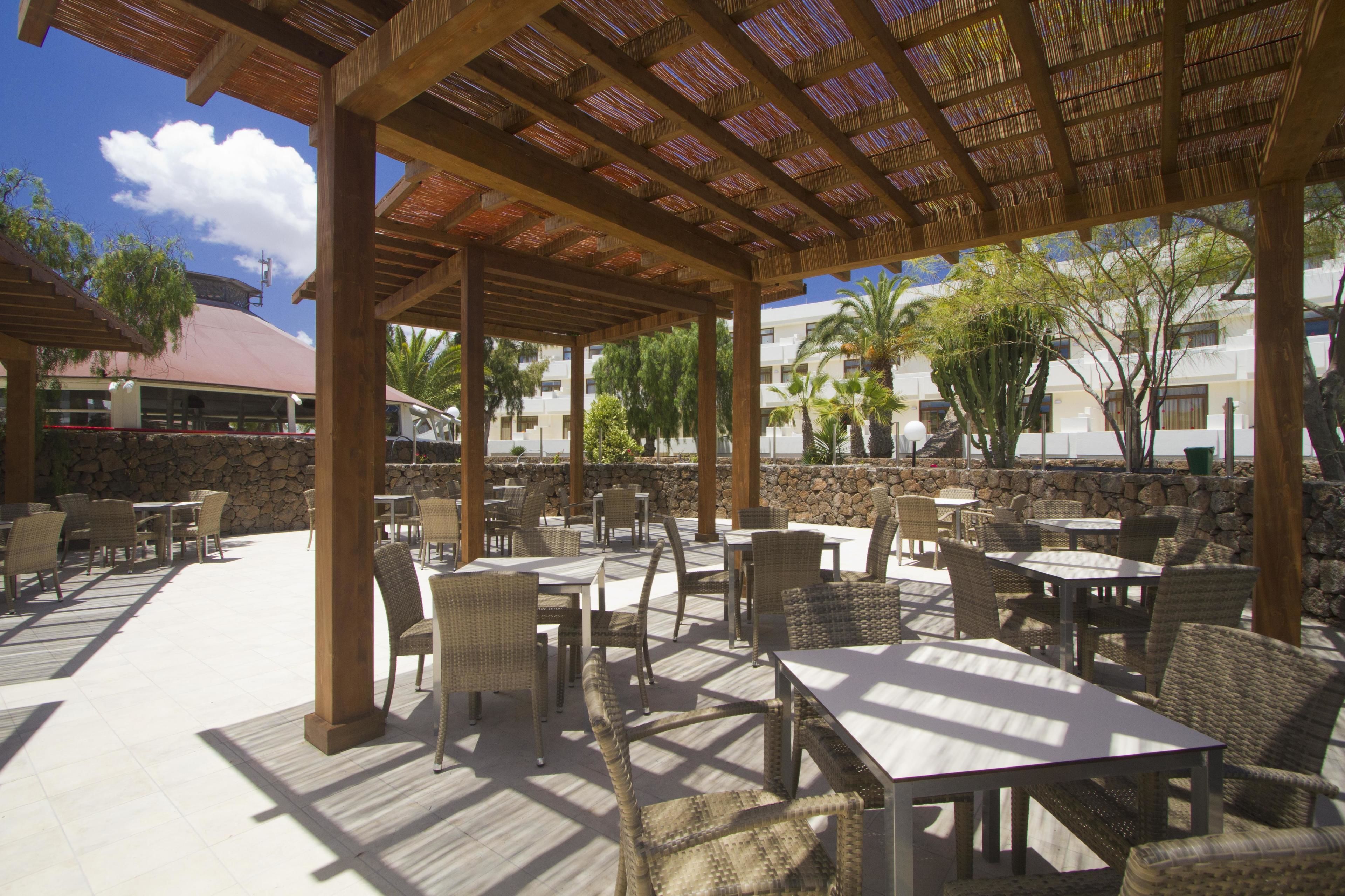 Un área de patio al aire libre con mobiliario de mimbre y techo de paja.