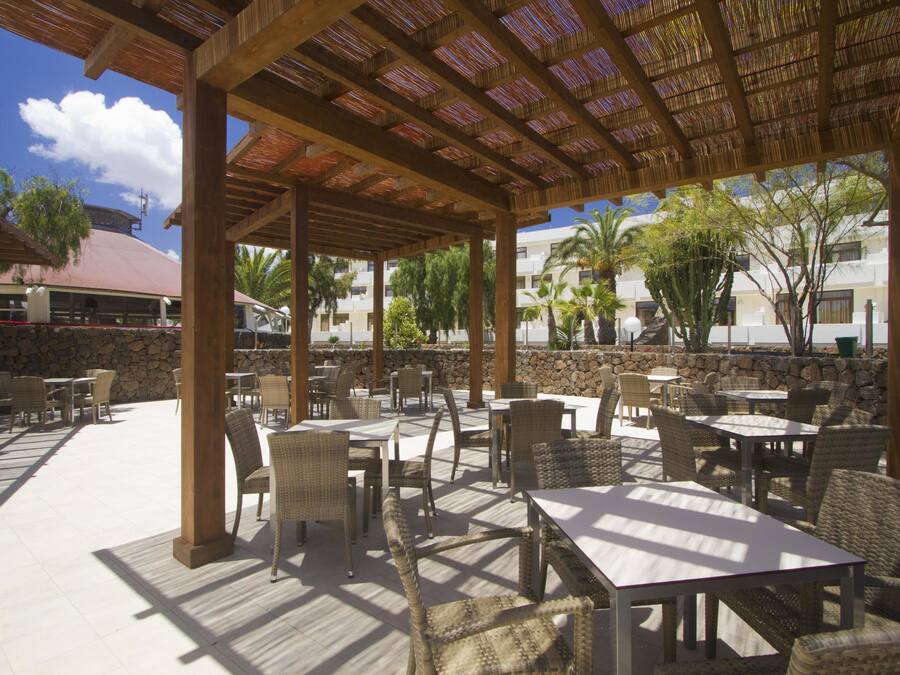 Un área de patio al aire libre con mobiliario de mimbre y techo de paja.