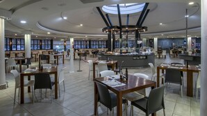Un restaurante espacioso con techos altos, ventanas grandes y una zona de bar central.
