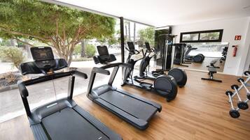 A gym with treadmills, exercise bikes, and free weights.