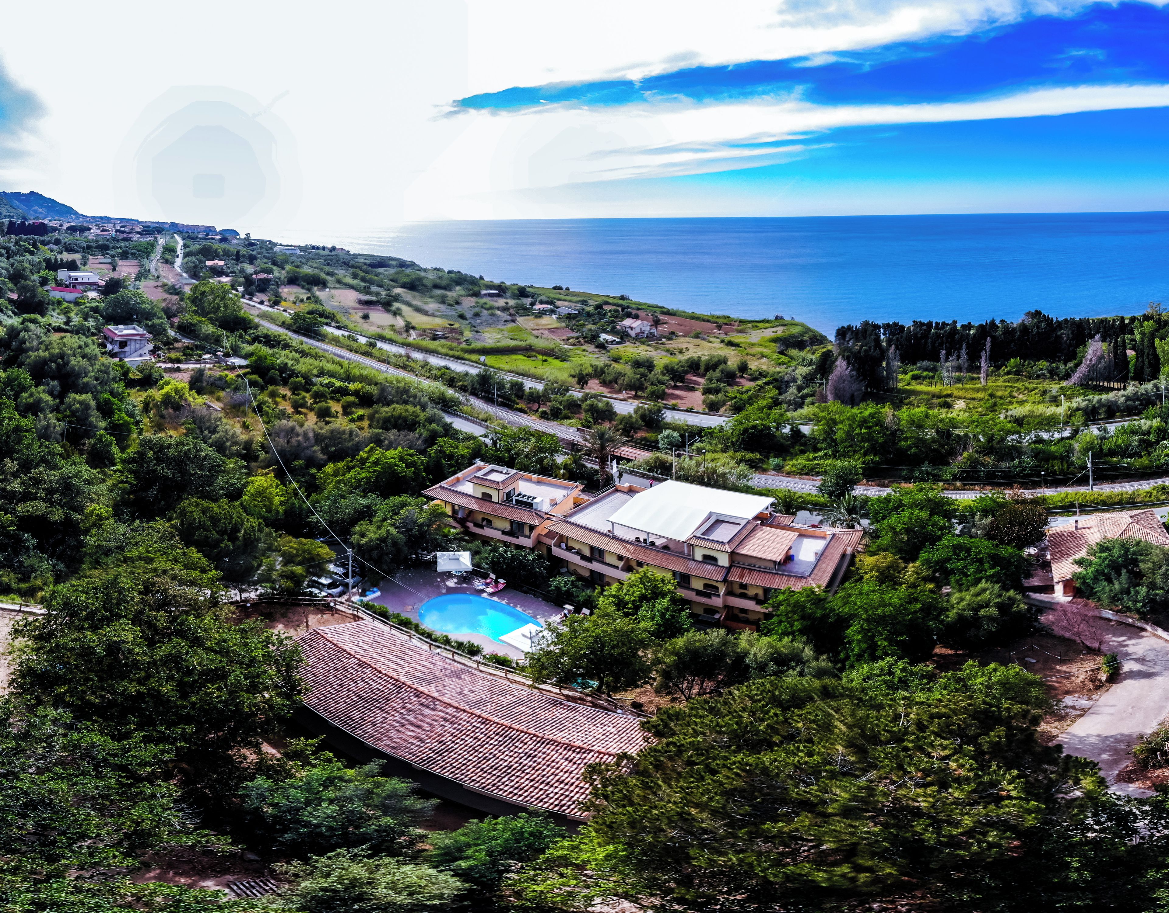 Une propriété située sur la côte, dotée d’une piscine, de maisons en terrasses et offrant une vue sur la mer.