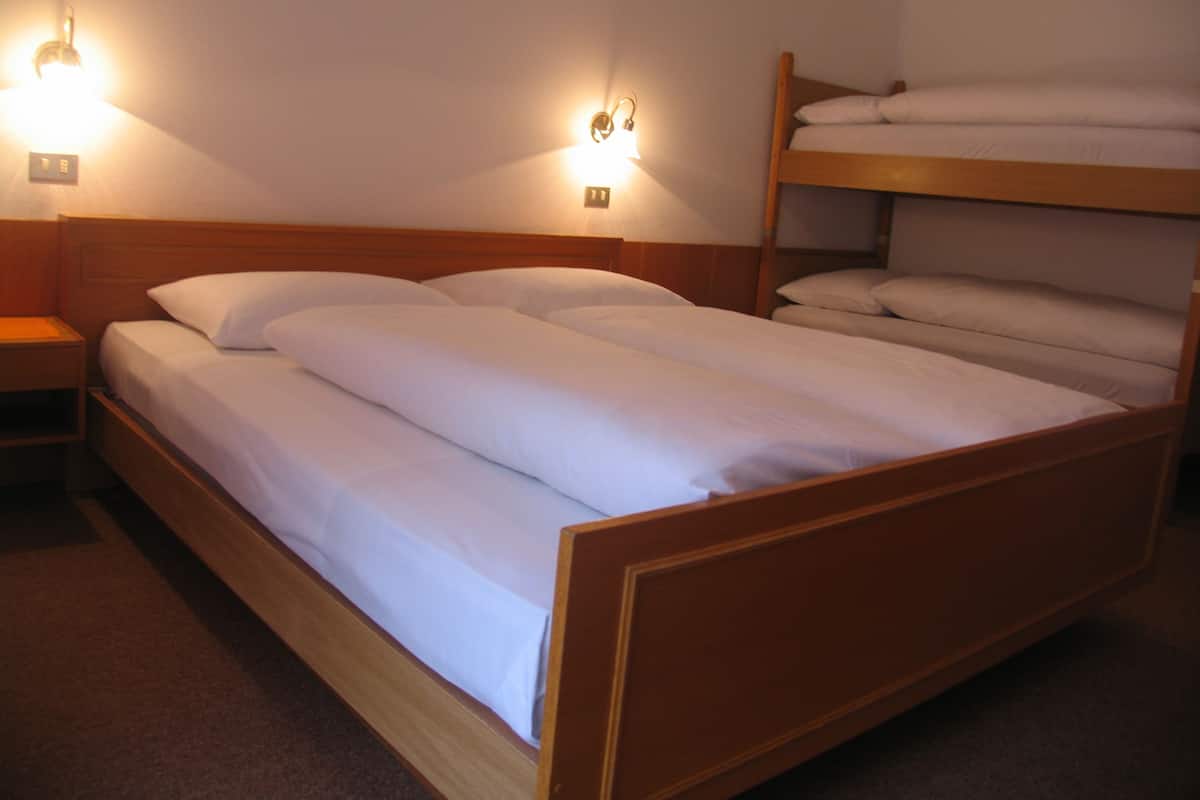 A bunk bed with white bedding and two wall-mounted lights.