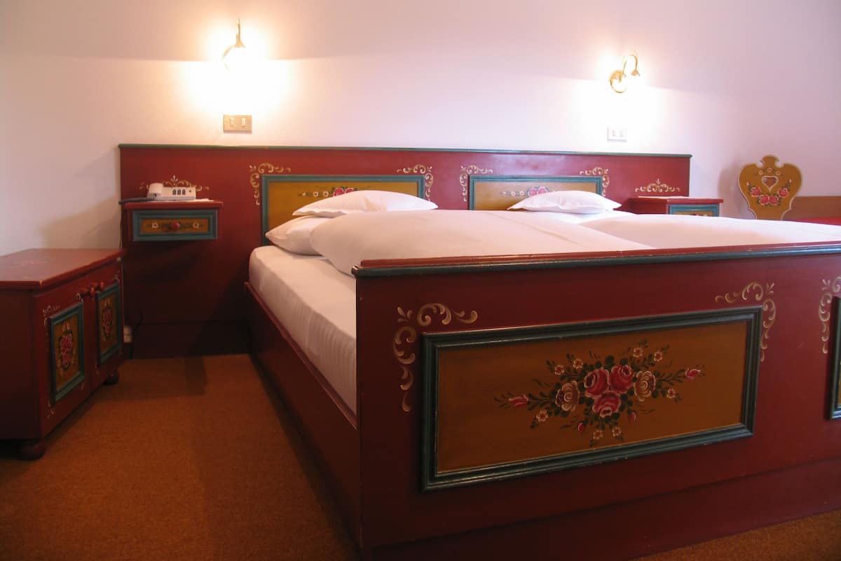 A neatly made bed with a floral headboard, two bedside tables, and wall-mounted lights.