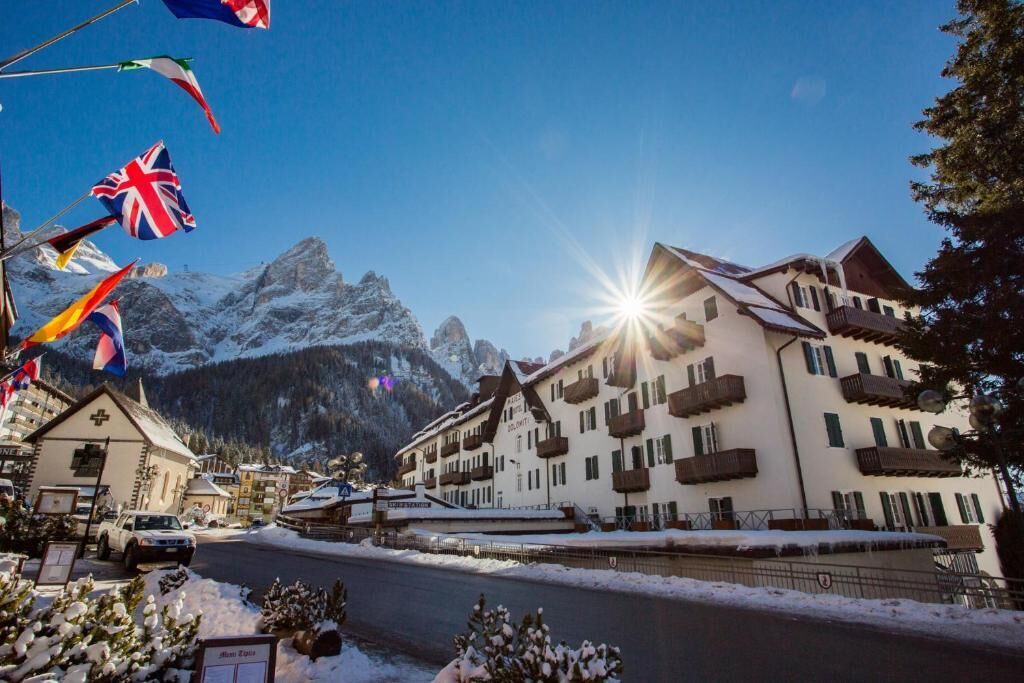 Un hôtel doté de nombreux balcons, avec une vue sur les montagnes et des drapeaux.