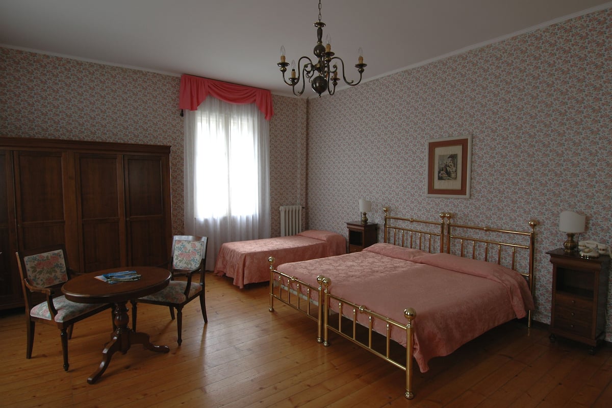 Ein Zimmer mit zwei Betten, einem Holztisch und einem Stuhl.