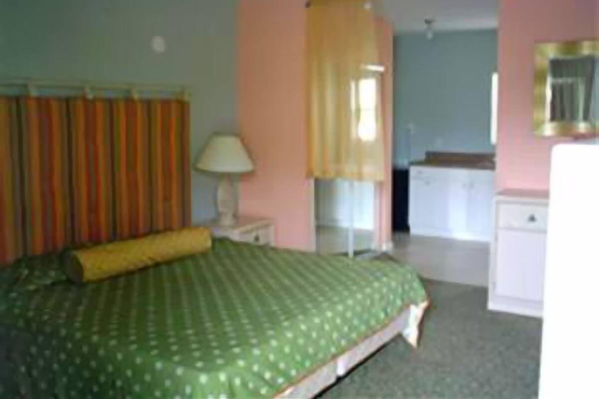 A bedroom with a bed, a nightstand, a lamp, a dresser, and a mirror.