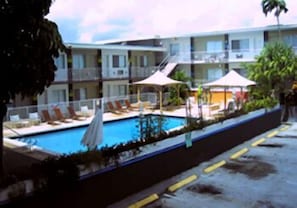 Un hôtel doté d’une piscine, de chaises longues et d’un espace abrité.