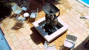 En udendørs terrasse med bålsted, siddepladser og en swimmingpool.
