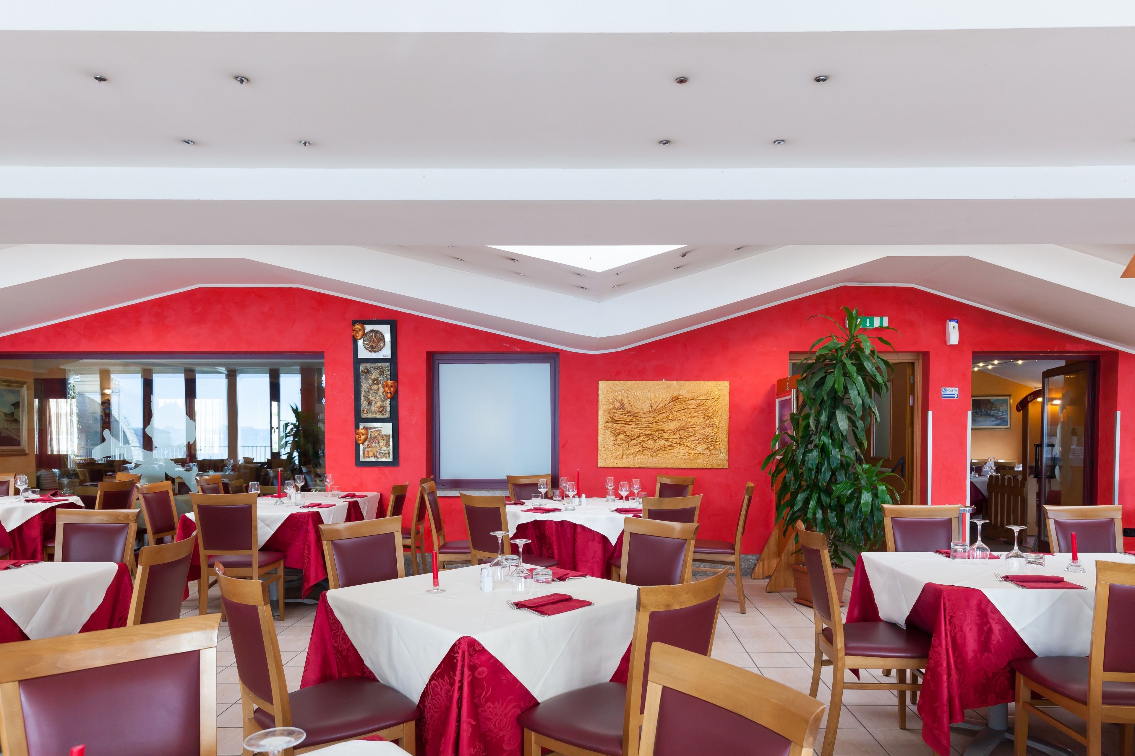 A restaurant with red walls, white tables, and red tablecloths.