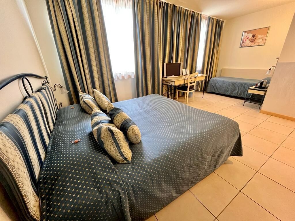 Une chambre d’hôtel avec un lit, un bureau, une chaise et une petite table.