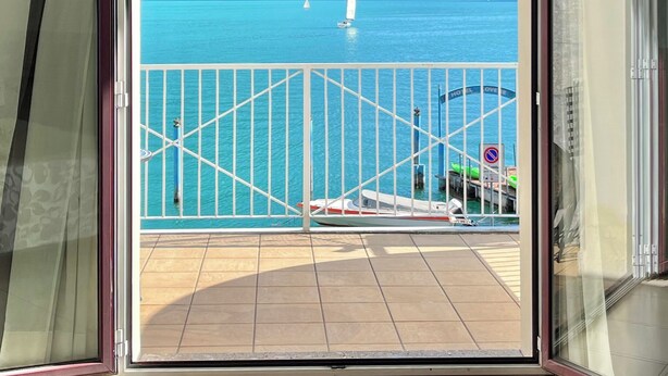 A view from a balcony with a clear sky, turquoise sea, and distant mountains. - Hotel Lovere Resort & Spa (Lovere)