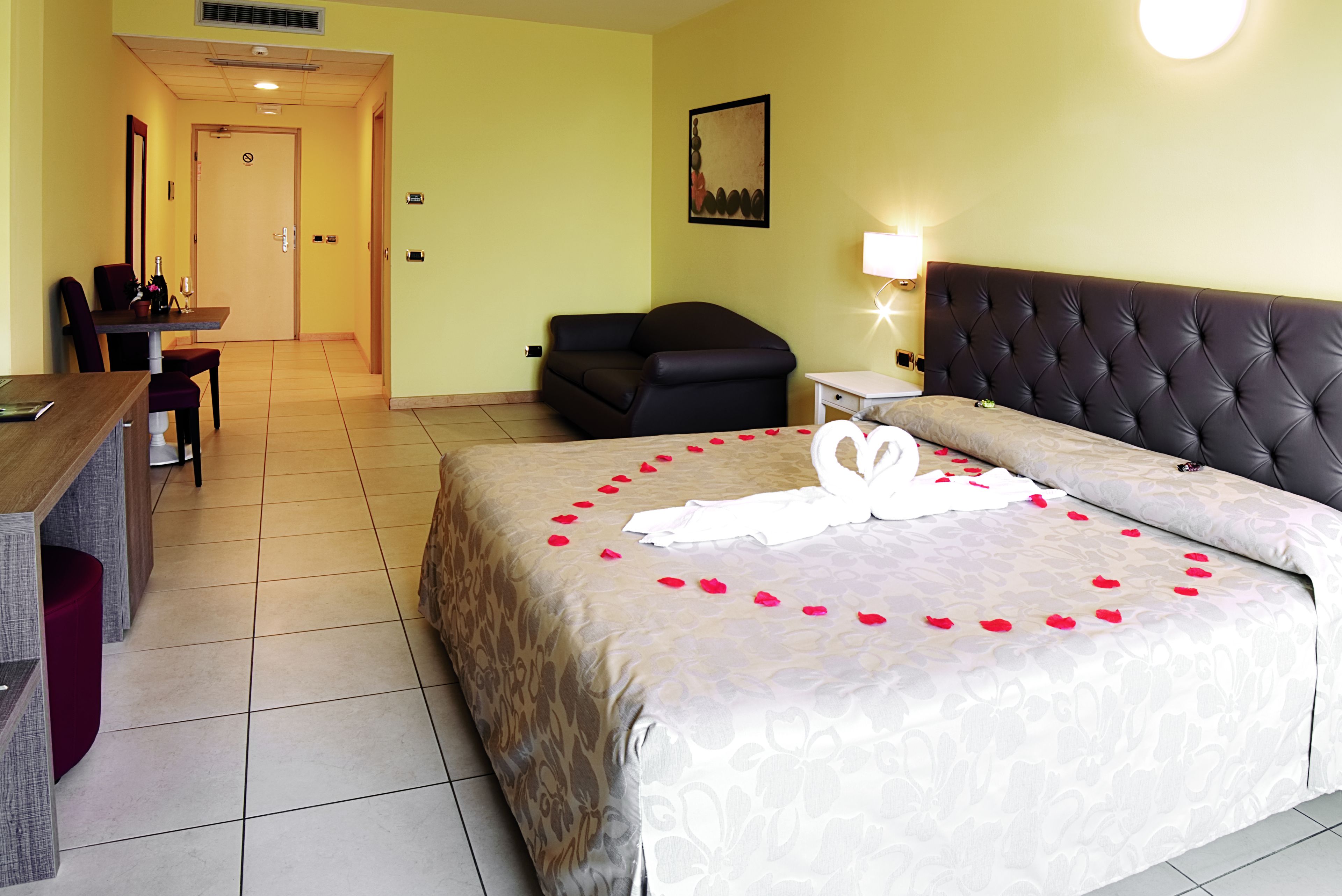 A hotel room with a bed, a desk, a chair, and a sofa.