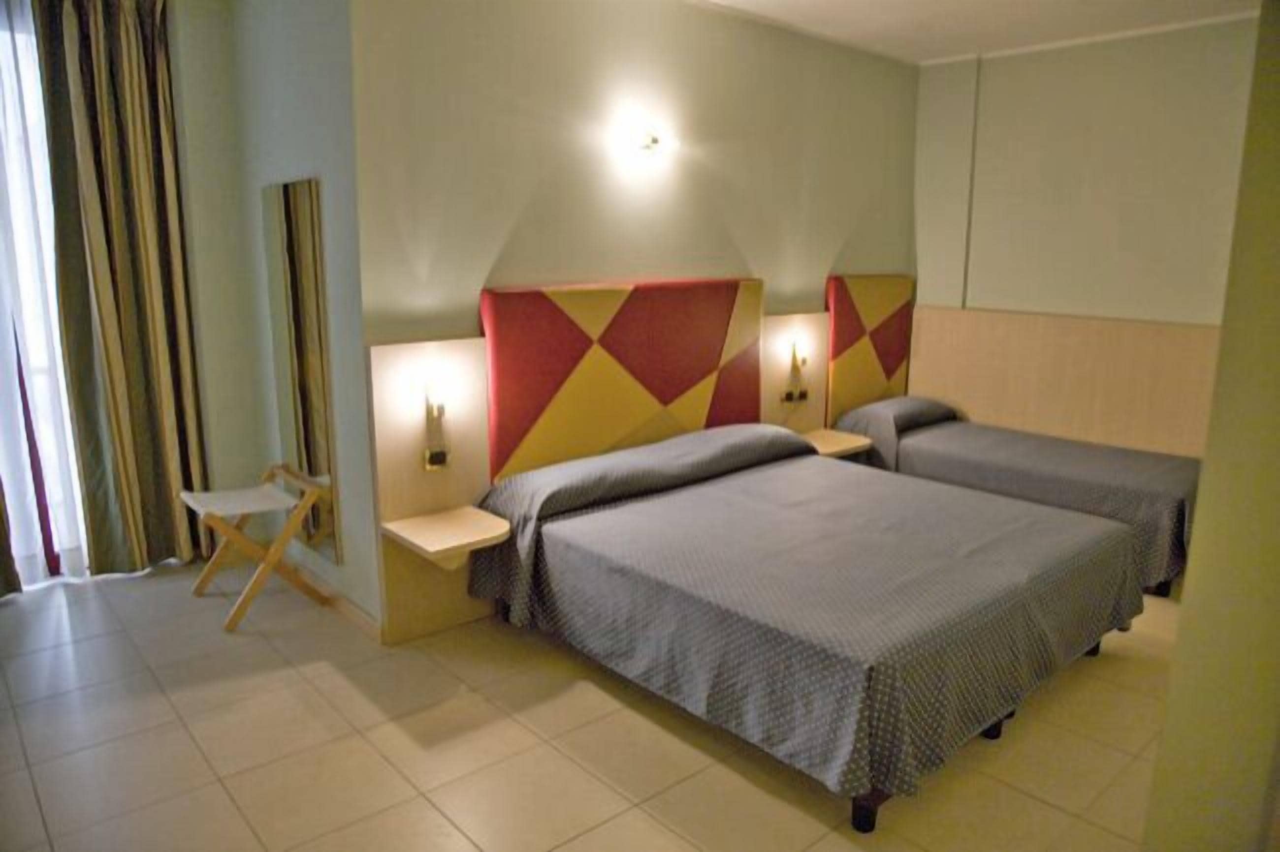 Une chambre d’hôtel avec deux lits, un petit bureau et une chaise.