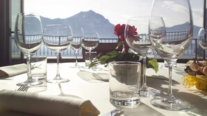 A table set for dining with wine glasses and a water glass, overlooking a mountainous landscape. - Hotel Lovere Resort & Spa (Lovere)