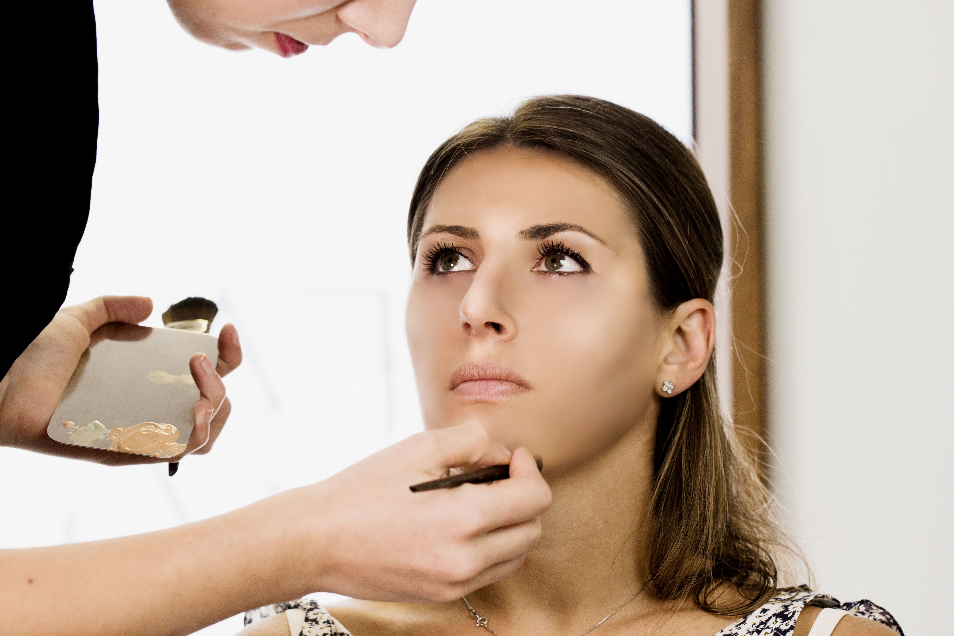 A person applying makeup to another individual.