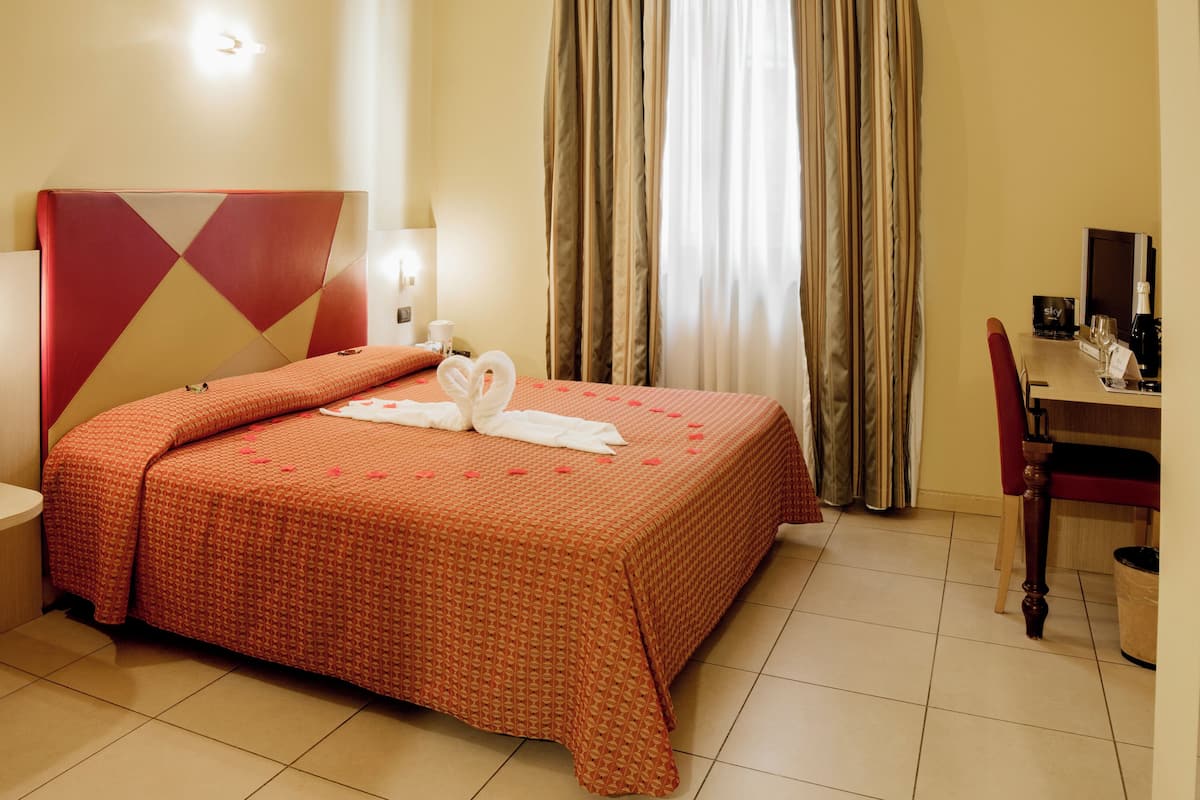 Ein Hotelzimmer mit Bett, Schreibtisch, Stuhl und Nachttisch.