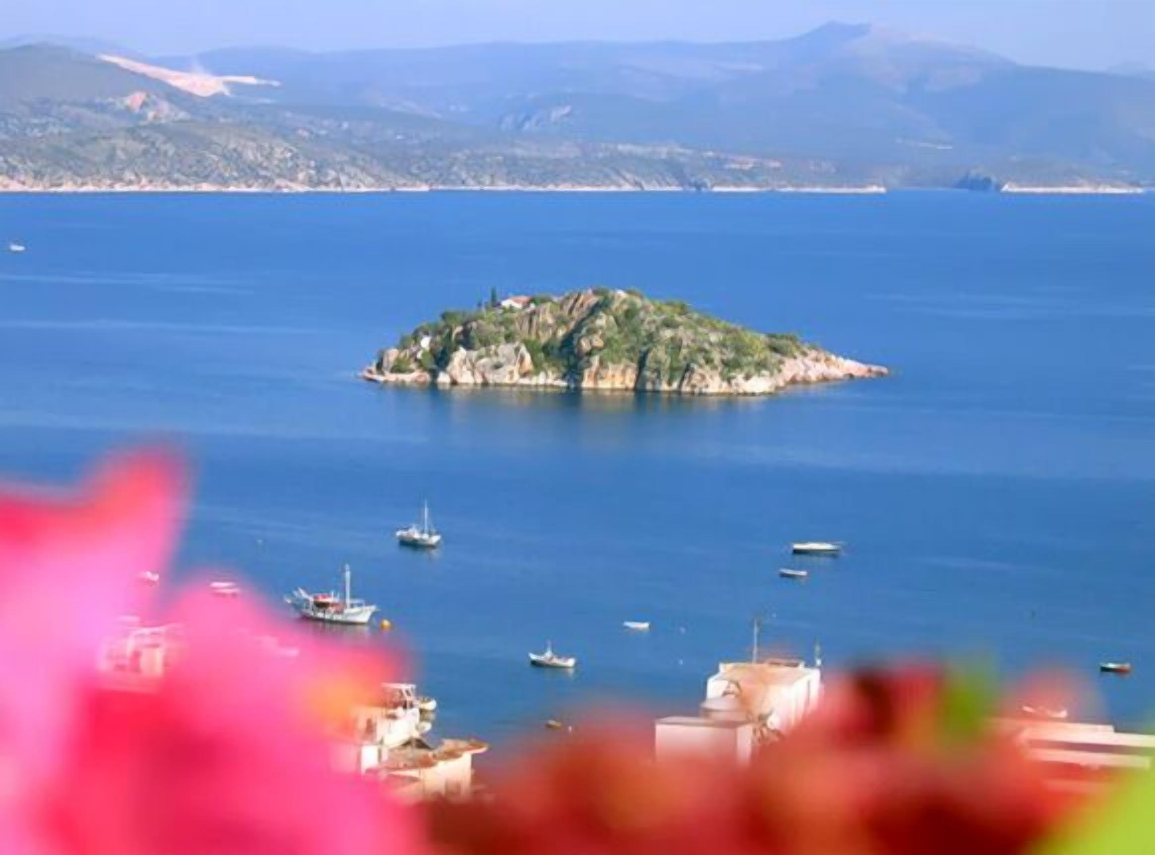 A coastal view with a small island and boats in the water.