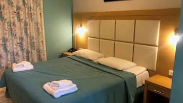 A hotel room with a large bed, two bedside tables, a nightstand, a telephone, and a painting on the wall.