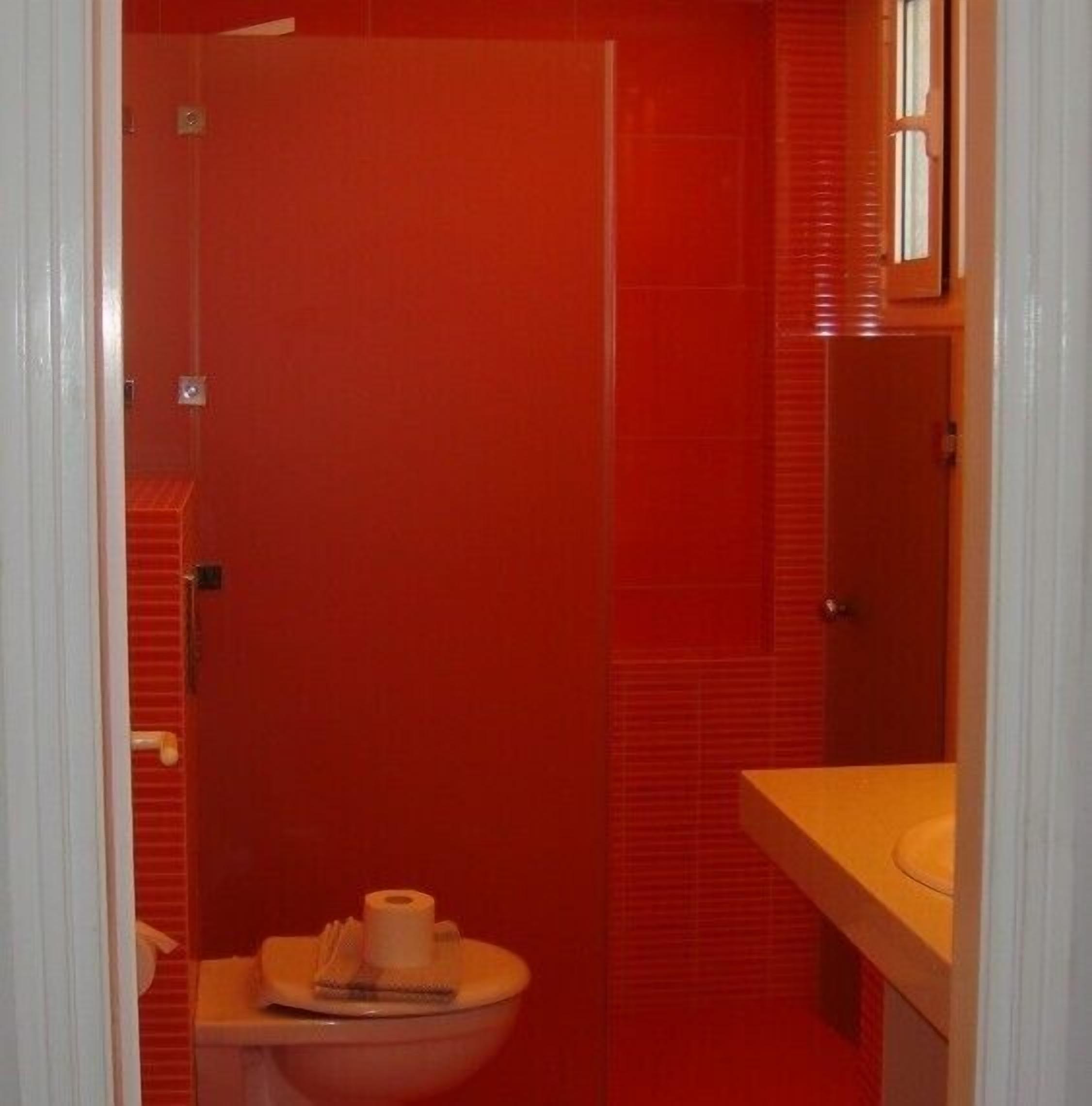 A bathroom with red walls, a white toilet, and a sink.