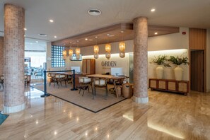 Un hall d’hôtel moderne avec un comptoir d’accueil, un espace salon et un panneau indiquant « JARDIN ».