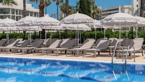 A swimming pool with lounge chairs and striped umbrellas. - Cala Millor Garden, Adults Only (Sant Llorenc des Cardassar)
