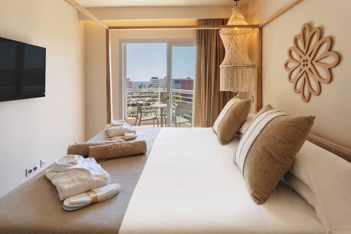 Ein Hotelzimmer mit Bett, Fernseher, Balkon mit Blick und einer Kristallleuchter.