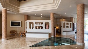 A spacious lobby with a glass floor, a seating area, and a wall with decorative niches. - Cala Millor Garden, Adults Only (Sant Llorenc des Cardassar)
