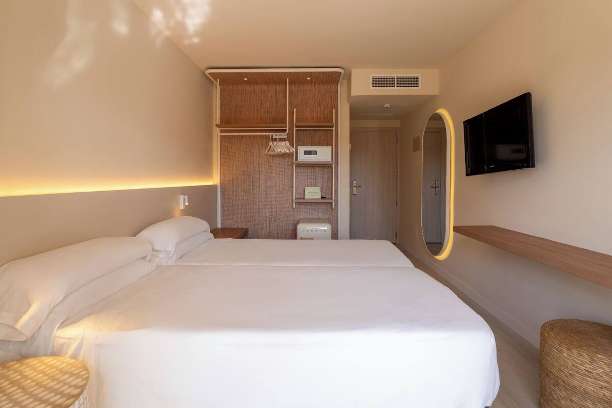 Ein Hotelzimmer mit einem großen Bett, einem Schrank, einem Fernseher und einem Spiegel.
