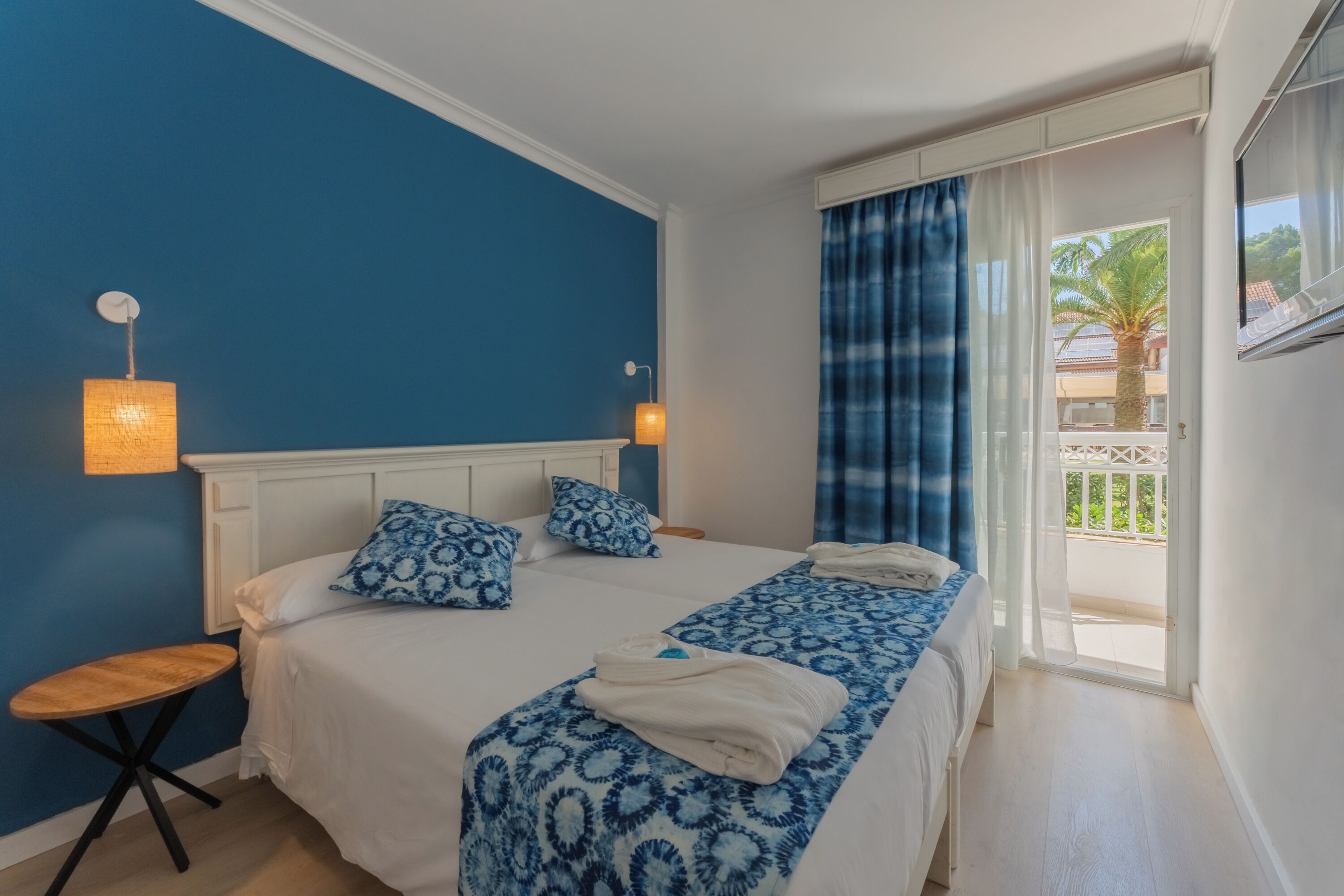 Ein Zimmer mit Bett, Nachttisch und einem Vorhangfenster.