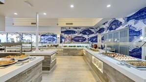 A buffet area with seafood-themed wall art, multiple serving stations, and a variety of food options. - Aparthotel Green Garden (Capdepera)