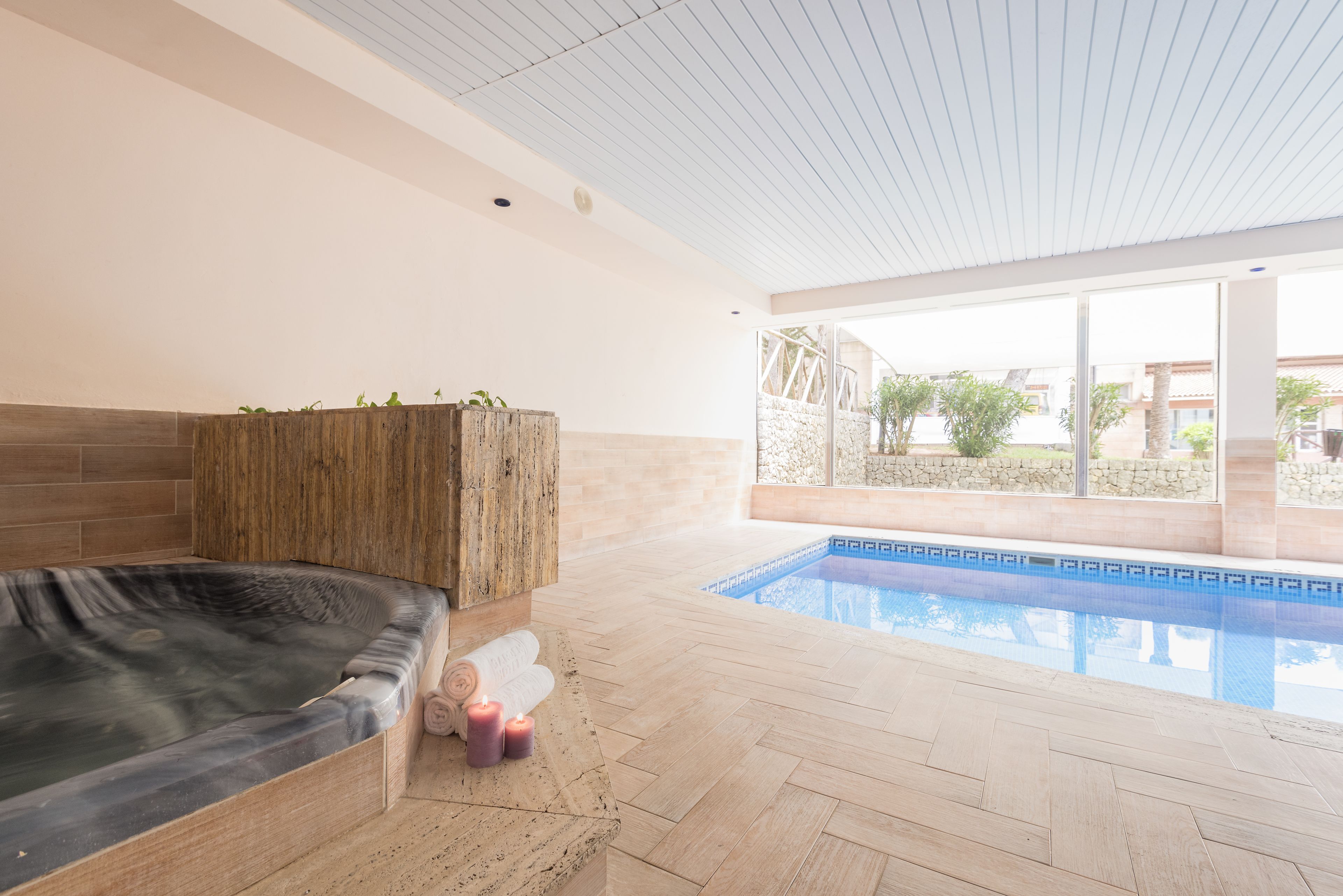 Un espace bien-être comprenant un jacuzzi, un banc en bois et une piscine.