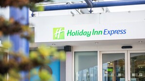 The exterior of a Holiday Inn Express hotel with a prominent green and blue logo, automatic doors, and a glass entrance. - Holiday Inn Express Ramsgate - Minster by IHG (Ramsgate)