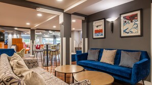 A modern lounge area with a blue sofa, patterned cushions, and a wooden coffee table. - Holiday Inn Express Ramsgate - Minster by IHG (Ramsgate)