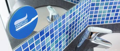 A bathroom with blue mosaic tiles, a chrome faucet, and a circular sign with text.