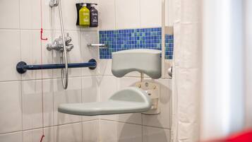A bathroom with a wheelchair-accessible shower, grab bars, and a tiled wall.