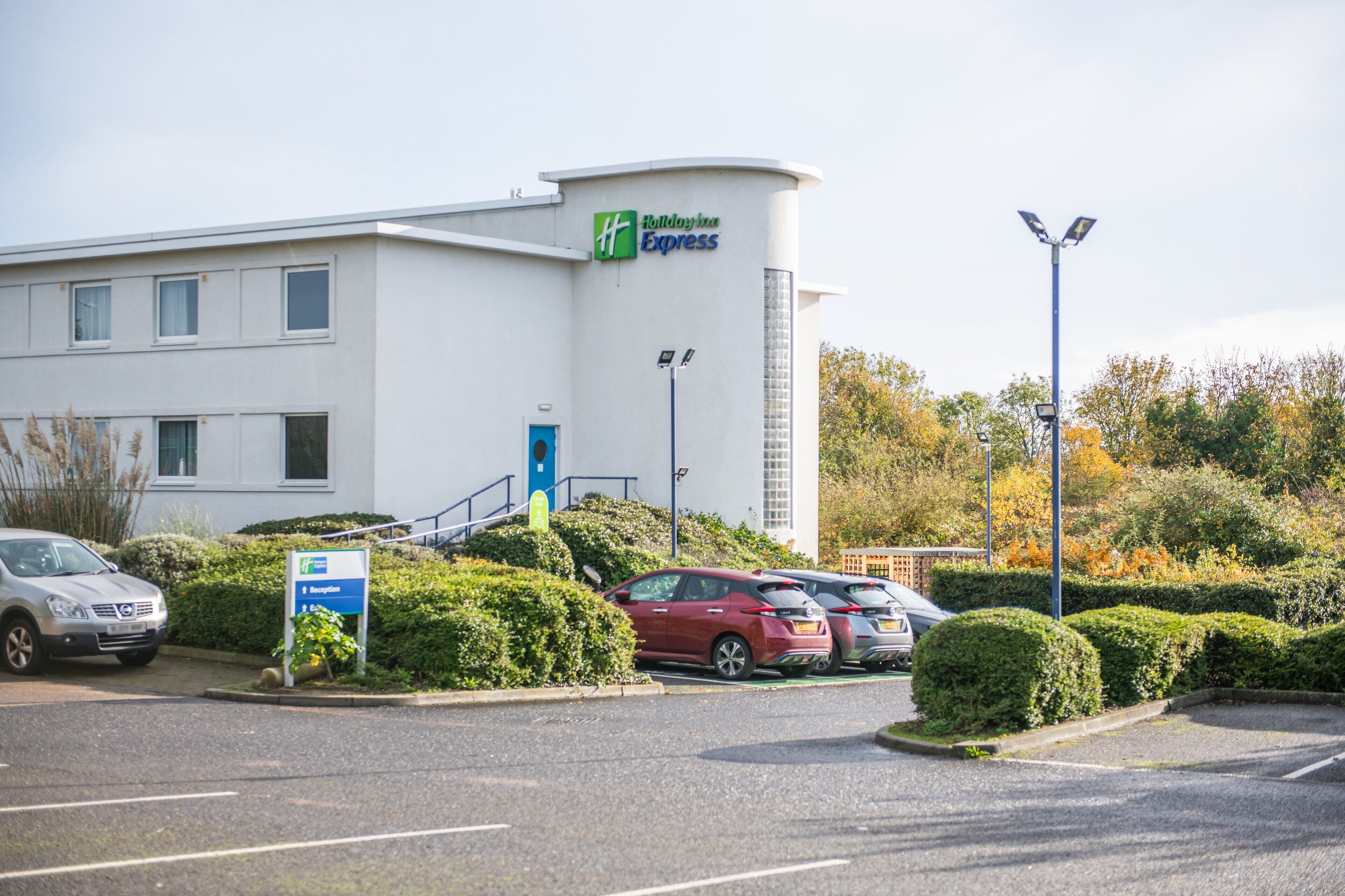 A Holiday Inn Express building with a reception area, parking lot, and surrounding greenery.