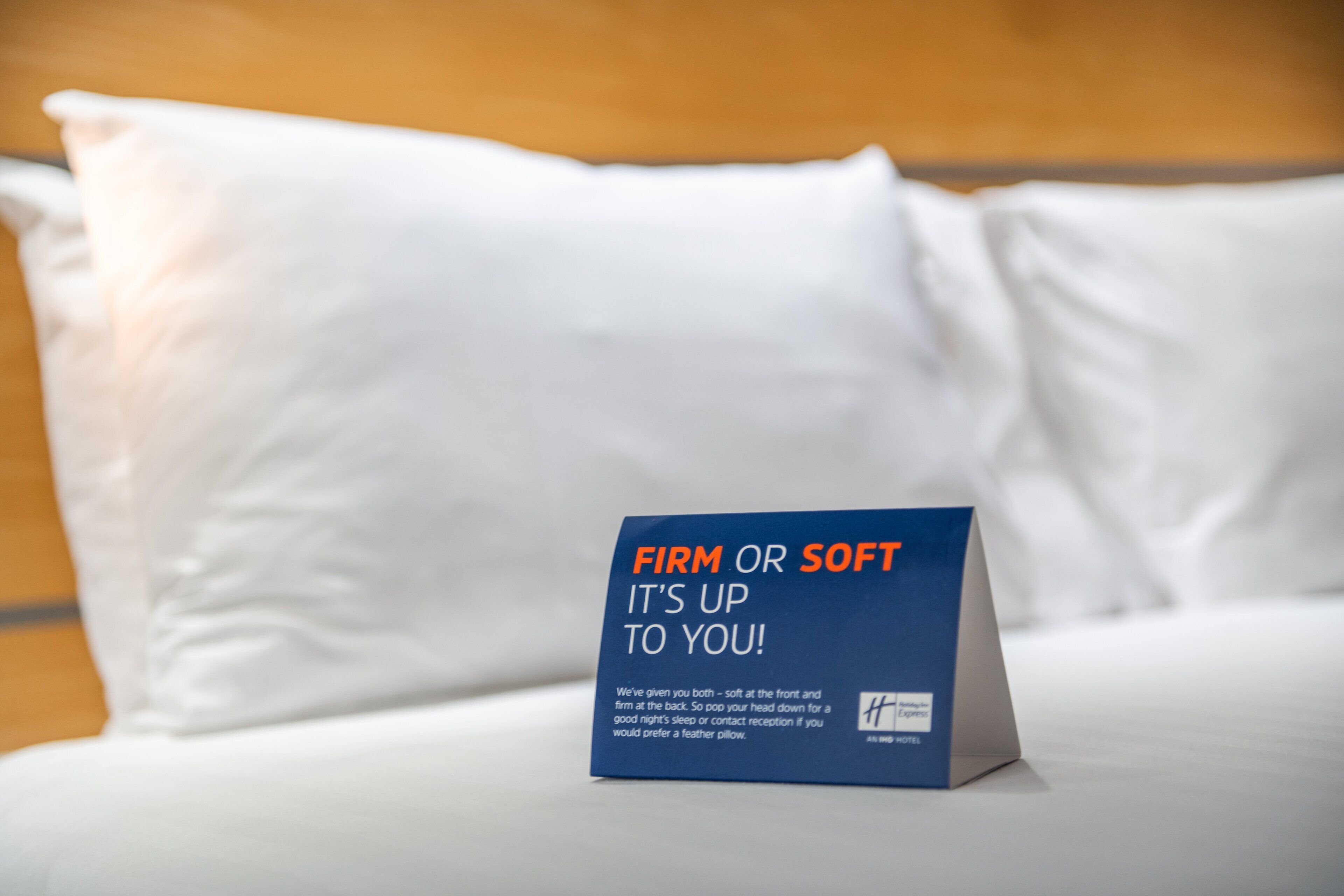 Una cama con una almohada y un letrero que dice "FIRME O SUAVE, TÚ DECIDES!"
