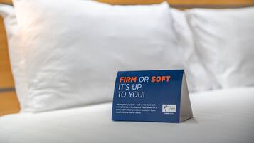 Een bed met een kussen en een bord waarop staat: 'HARD OF ZACHT, JIJ KIEST!'