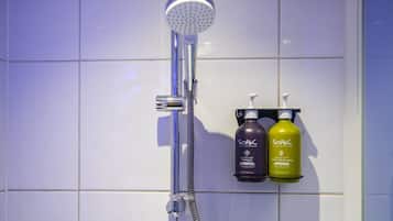 Ducha con cabezal de ducha de mano y dos botellas de champú y gel de baño Soak sobre un estante fijado a la pared.