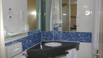 A bathroom with a glass-enclosed shower, a sink with a dark countertop, and blue-tiled walls.