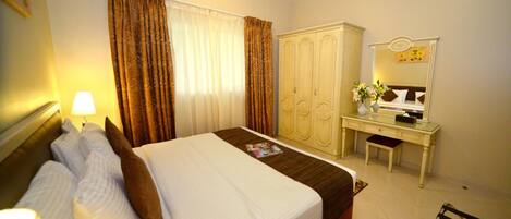 A hotel room with a bed, a desk, a wardrobe, and a mirror.