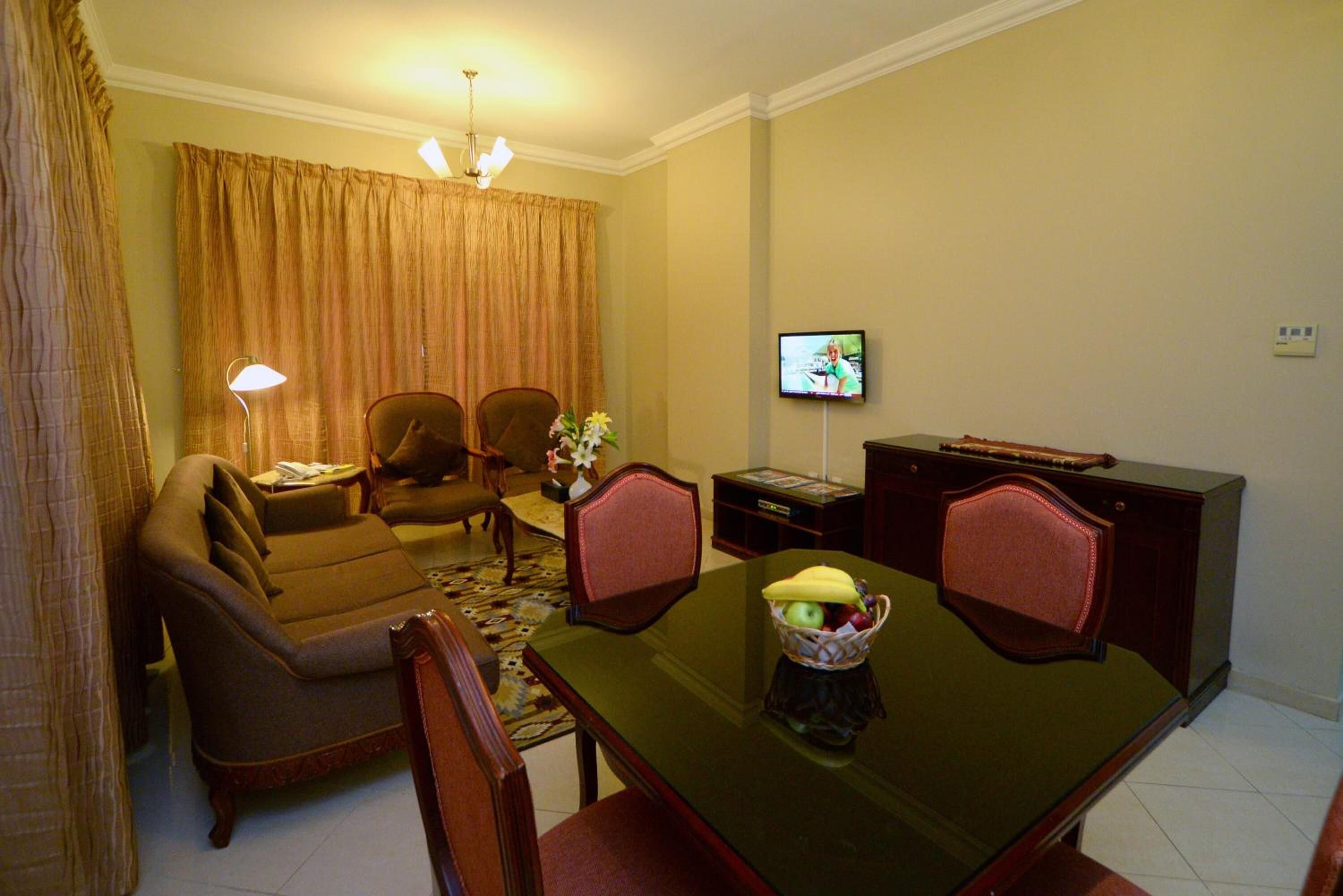 A dining area with a table, chairs, a television, and a sofa.