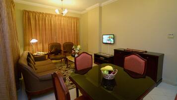 A dining area with a table, chairs, a television, and a sofa.