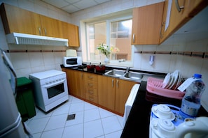 A kitchen with wooden cabinets, a microwave, a stove, and a window with a view. - Emirates Stars Hotel Apartments Sharjah (Sharjah)