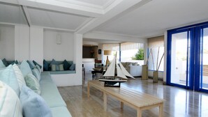 A modern living room with a light-colored sofa, a wooden coffee table, and a sailboat model. - MR Mar Suites (Vina del Mar)