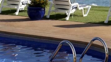 A poolside area with lounge chairs and a potted plant.
